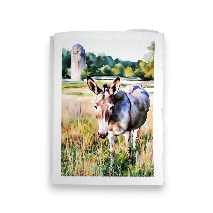 The FEARRINGTON SIGNATURE COLLECTION - WATERCOLOR GREETING CARD "JASPER" by PICTURE SALON features a watercolor donkey in tall grass with trees and a stone structure, perfect for textured paper greeting cards.