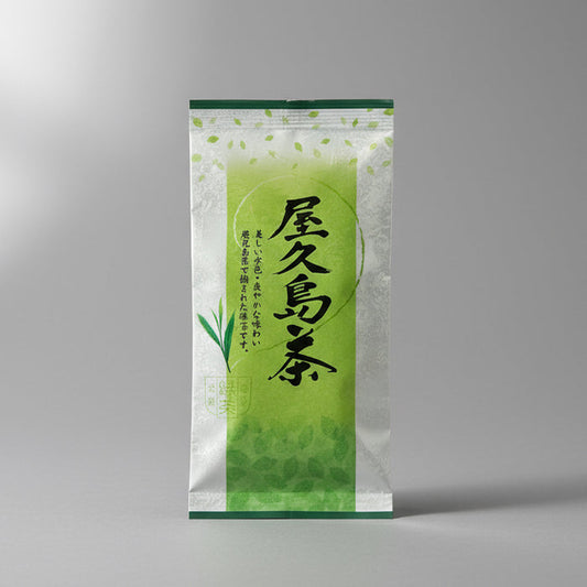 A packaged bag of #0133.K2 Yamane-en: First Flush Saemidori Fukamushicha from Yakushima Island, displayed on a wooden surface.