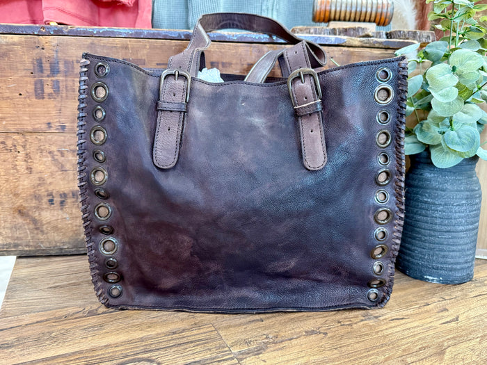 Grommeted leather tote bag with dark blue front and side metal eyelet trim