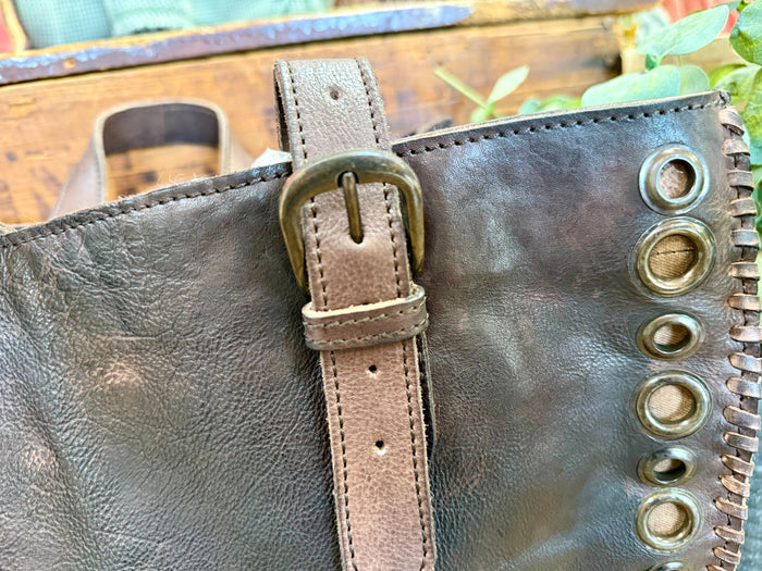 Leather tote bag handle with stitched strap and brass grommets along edge