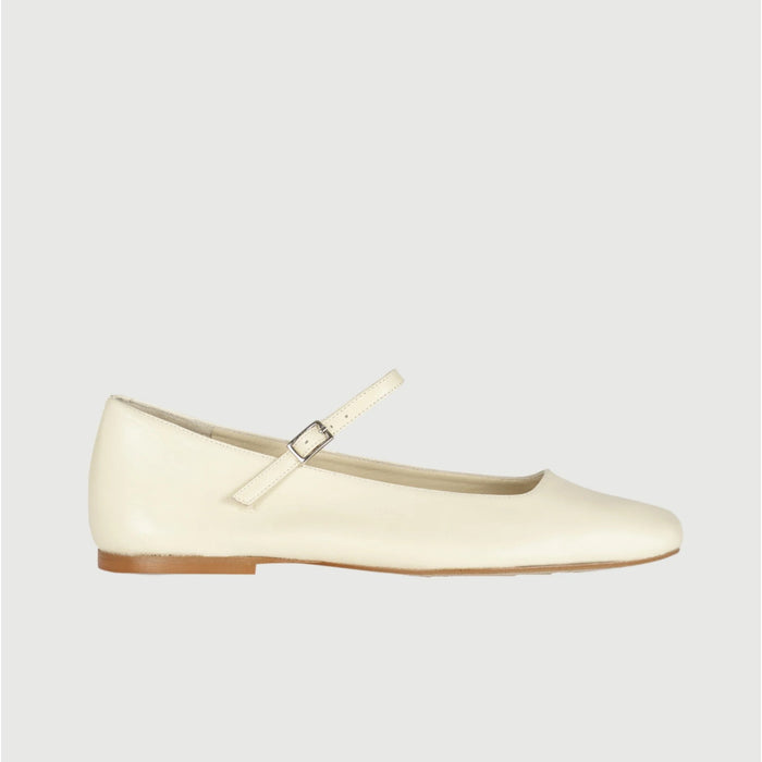 The AUGUSTA - JULIETA MARY JANE by AUGUSTA is a black leather Mary Jane flat with a thin strap and buckle, light brown sole, and subtle square toe, handcrafted in Spain and shown on a light gray background.