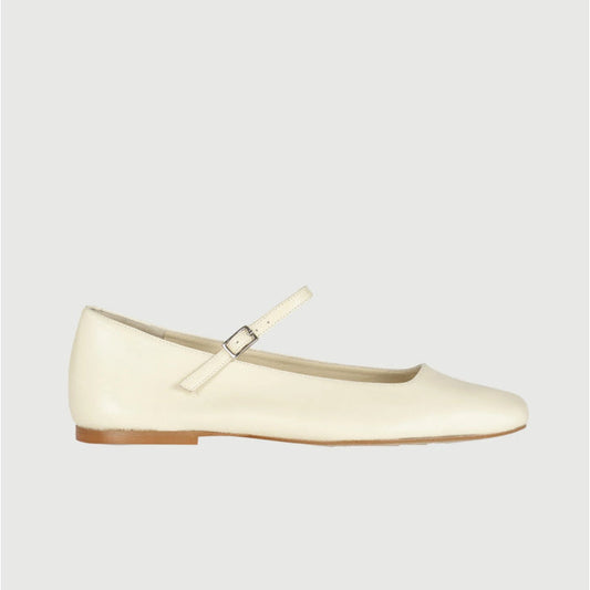 The AUGUSTA - JULIETA MARY JANE by AUGUSTA is a black leather Mary Jane flat with a thin strap and buckle, light brown sole, and subtle square toe, handcrafted in Spain and shown on a light gray background.