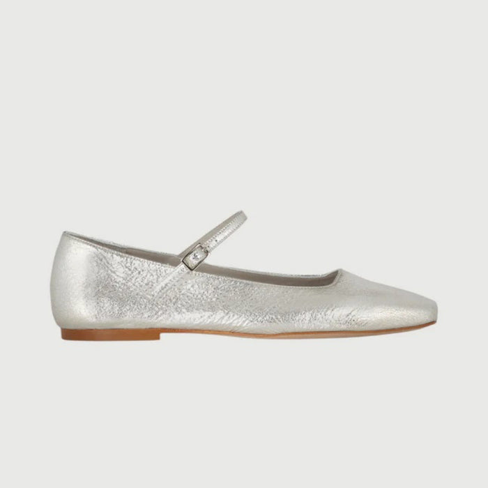 The AUGUSTA - JULIETA MARY JANE by AUGUSTA is a black leather Mary Jane flat with a thin strap and buckle, light brown sole, and subtle square toe, handcrafted in Spain and shown on a light gray background.