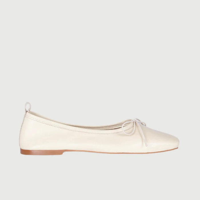 The AUGUSTA - SIENNA BALLET FLAT by AUGUSTA, handcrafted in Spain, showcases a silver finish with a front bow, low brown sole, and heel pull tab, displayed in side profile against a plain light background.