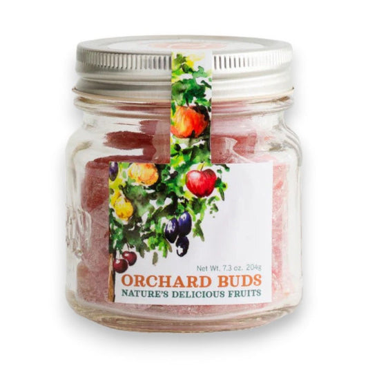 A glass jar labeled "BUTTERFIELDS - ORCHARD BUDS," branded as BUTTERFIELDS with the tagline "Nature's Delicious Fruits,” containing pink candies. The jar has a metal lid and a colorful label featuring illustrations of fruit-bearing branches with apples, plums, and peaches.