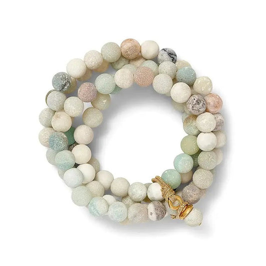 The CC & CO by Catherine Canino Sally Bracelet in Druzy Quartz is a stretchy bracelet made with round, semi-precious beads in white, beige, green, and gray shades. It features a hint of blue druzy quartz and a gold clasp for an elegant touch.