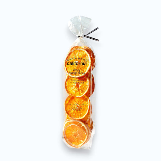 A clear plastic bag of DARDIMANS - CRISPY ORANGE SLICES by DARDIMANS CALIFORNIA CRISPS stands upright on a light surface—vitamin-rich snacks made from premium California oranges.