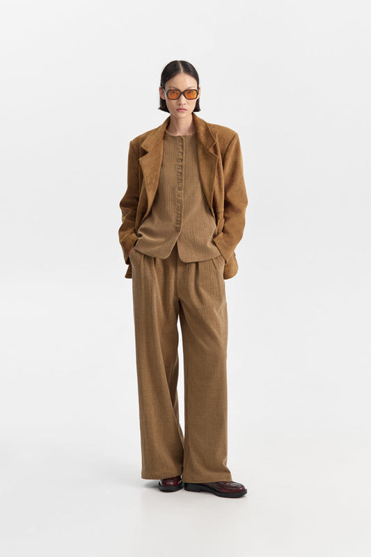 A person wearing ELEH CLASSIC WIDE LEG TROUSERS and a matching brown corduroy jacket, paired with brown shoes and large sunglasses, stands against a plain white background with hands in pockets.