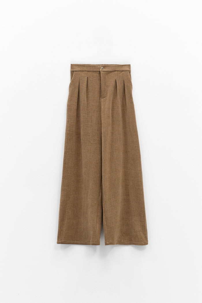 A person wearing ELEH CLASSIC WIDE LEG TROUSERS and a matching brown corduroy jacket, paired with brown shoes and large sunglasses, stands against a plain white background with hands in pockets.