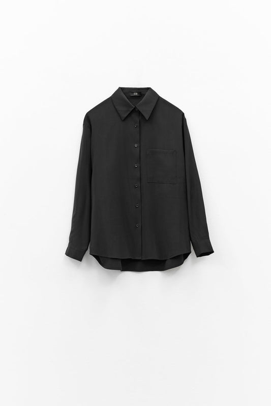 The ELEH - THE ESSENTIAL BLACK SHIRT, featuring long sleeves, a pointed collar, and chest pocket, hangs against a white background—ideal for those who value minimalist luxury.