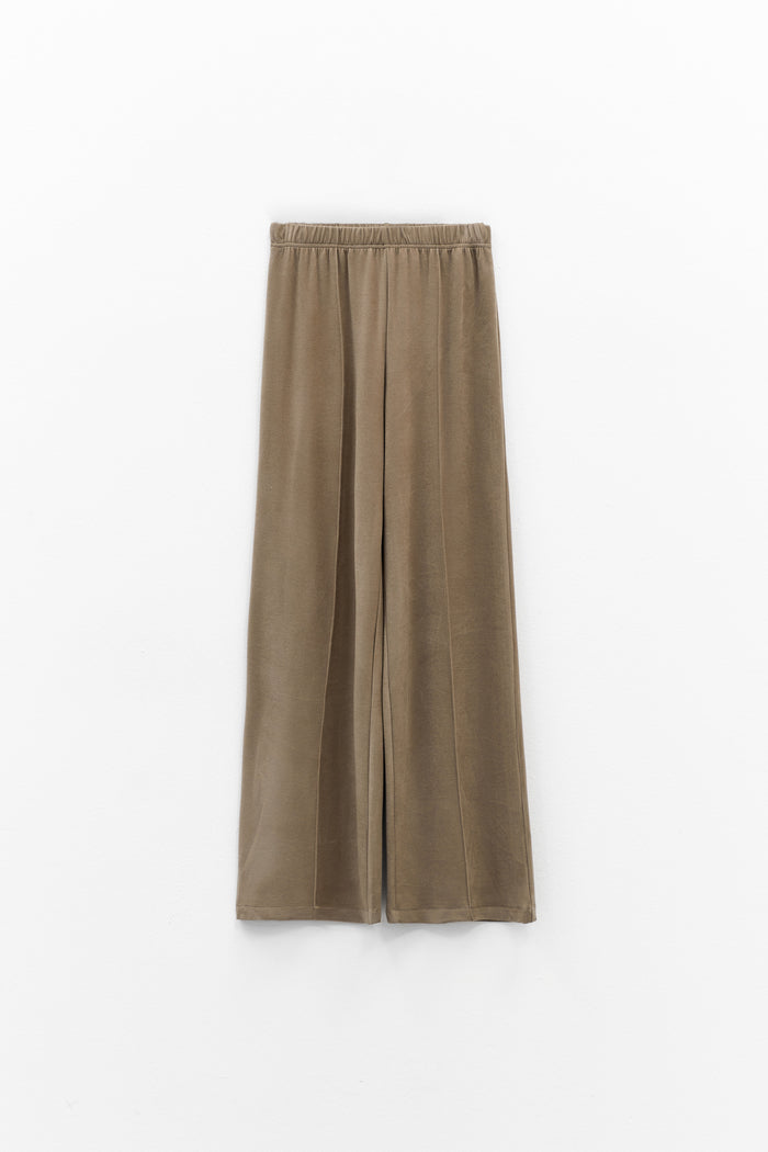 The ELEH - THE SCALA PULL ON SWEATPANT TROUSER by ELEH is a pair of loose-fitting, light brown, velvety pull-on trousers with an elastic waistband, shown against a plain white background.