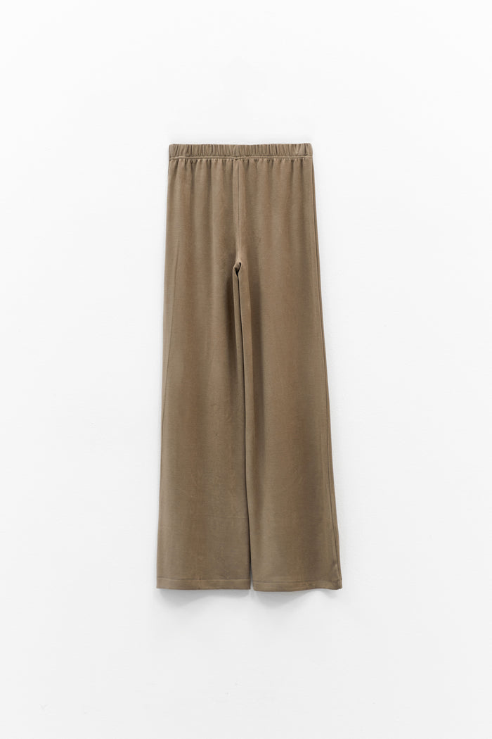 The ELEH - THE SCALA PULL ON SWEATPANT TROUSER by ELEH is a pair of loose-fitting, light brown, velvety pull-on trousers with an elastic waistband, shown against a plain white background.