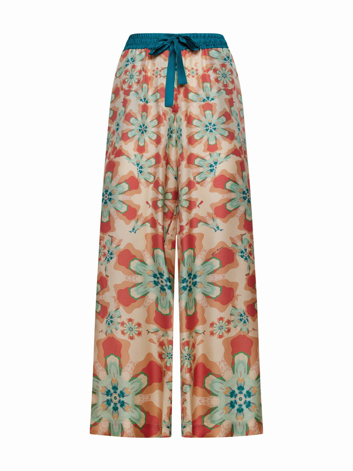 FRANCO FERRARI's ALOE SILK TROUSER is high-waisted with a wide-leg cut, showcasing a resort-style floral print in vibrant orange, teal, and pink on a light background with large blossoms for an eye-catching look.
