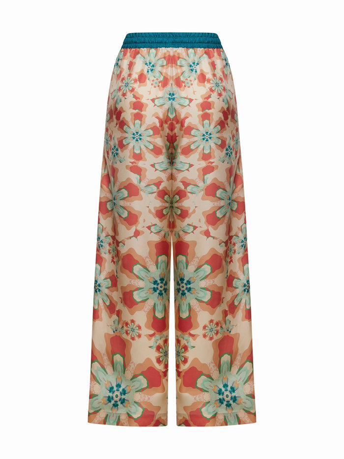 FRANCO FERRARI's ALOE SILK TROUSER is high-waisted with a wide-leg cut, showcasing a resort-style floral print in vibrant orange, teal, and pink on a light background with large blossoms for an eye-catching look.