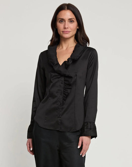 A woman with long dark hair wears the HINSON WU AMARA Long Sleeve Cotton Satin Shirt, featuring ruffled details on the collar and front, standing against a plain light background.
