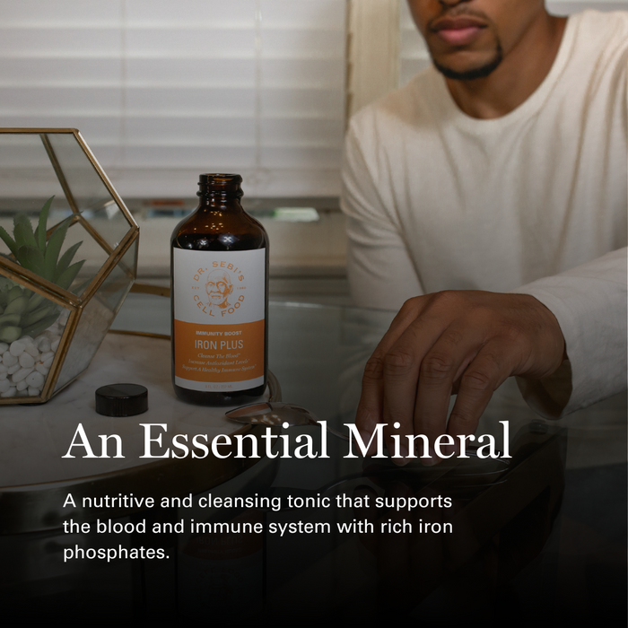 Man examining Dr. Sebi's Iron Plus tonic bottle on minimalist wellness display with plant and geometric décor.