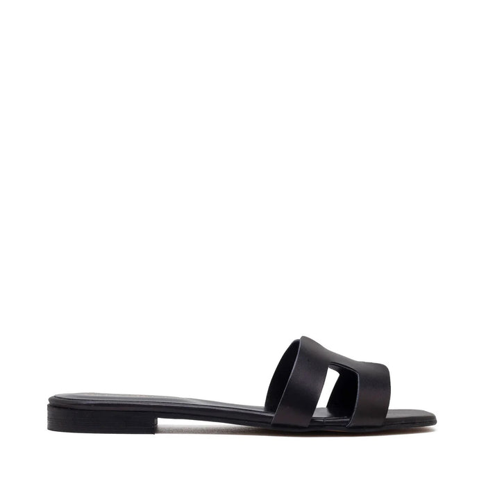 The MICHELE LOPRIORE - H SLIDE is a brown leather sandal with two wide straps, including one with a rectangular cutout, featuring a flat wooden sole. Made in Italy by MICHELE LOPRIORE, it's shown on a white background.