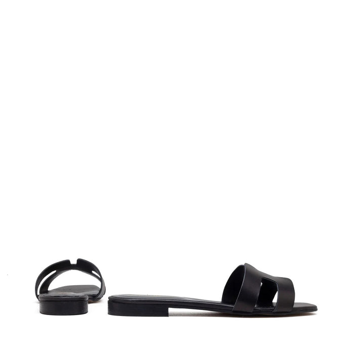 The MICHELE LOPRIORE - H SLIDE is a brown leather sandal with two wide straps, including one with a rectangular cutout, featuring a flat wooden sole. Made in Italy by MICHELE LOPRIORE, it's shown on a white background.