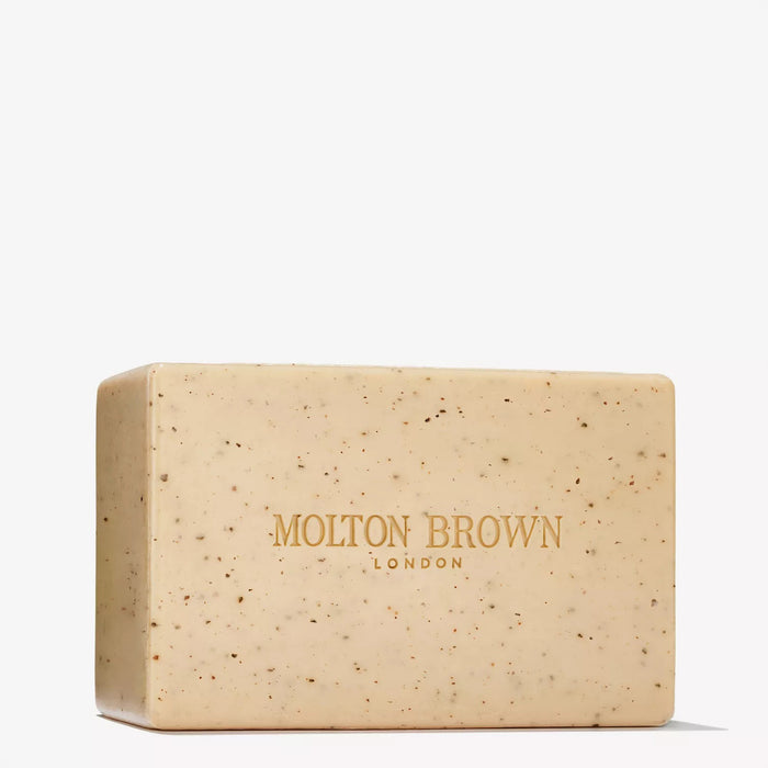 A rectangular beige MOLTON BROWN RE-CHARGE BLACK PEPPER BODY SCRUB BAR (250g) with small dark specks and "MOLTON BROWN LONDON" in gold across the front.