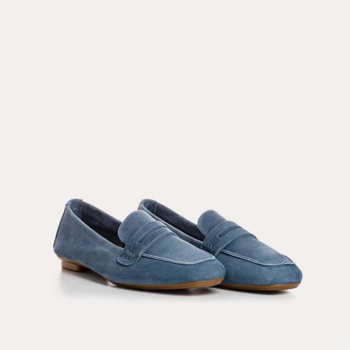 The REQINS - HEMA suede loafer in Blue Jean features a classic silhouette, minimalist design, penny strap, and brown soles, shown against a plain white background.