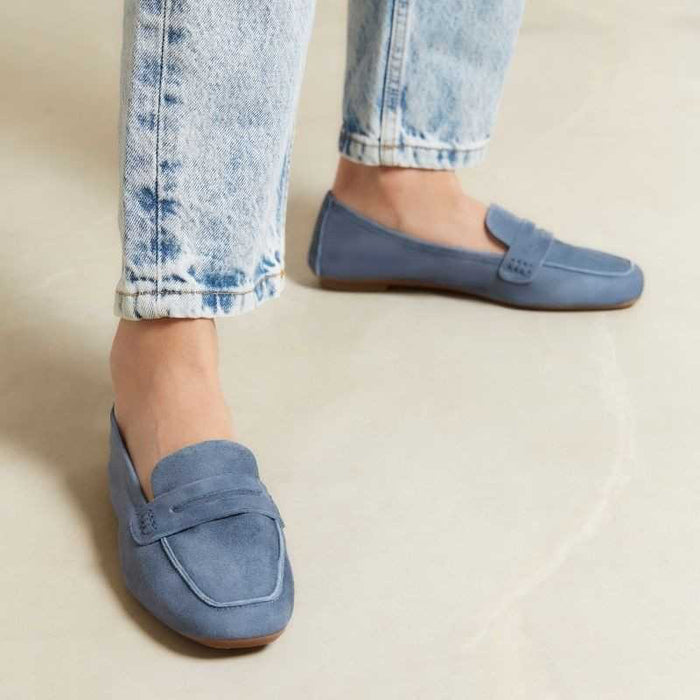 The REQINS - HEMA suede loafer in Blue Jean features a classic silhouette, minimalist design, penny strap, and brown soles, shown against a plain white background.