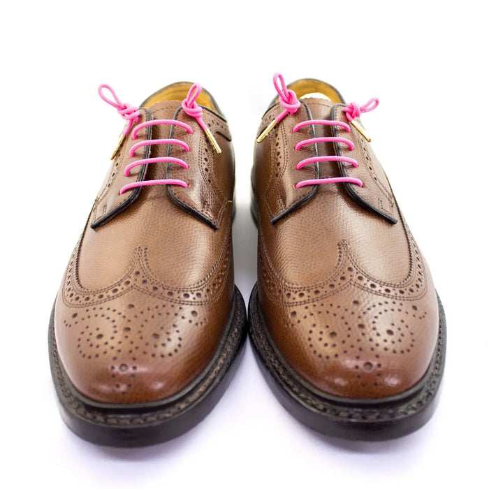 STOLEN RICHES - DRESS SHOELACES IN POONA PINK: Bright pink premium laces with gold aglets, neatly folded and wrapped in a white band labeled "STOLEN RICHES" with a crown logo.